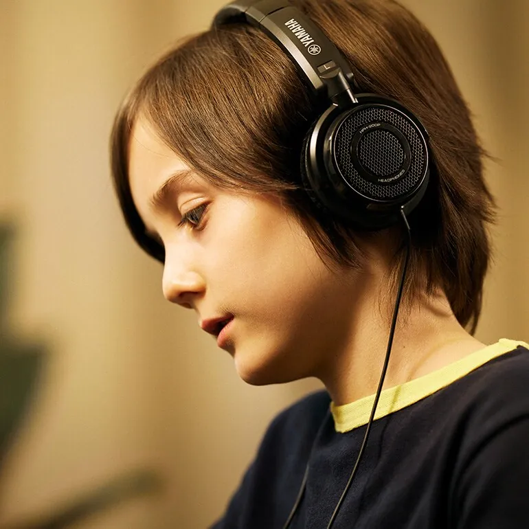 A child practising on a Yamaha piano through headphones
